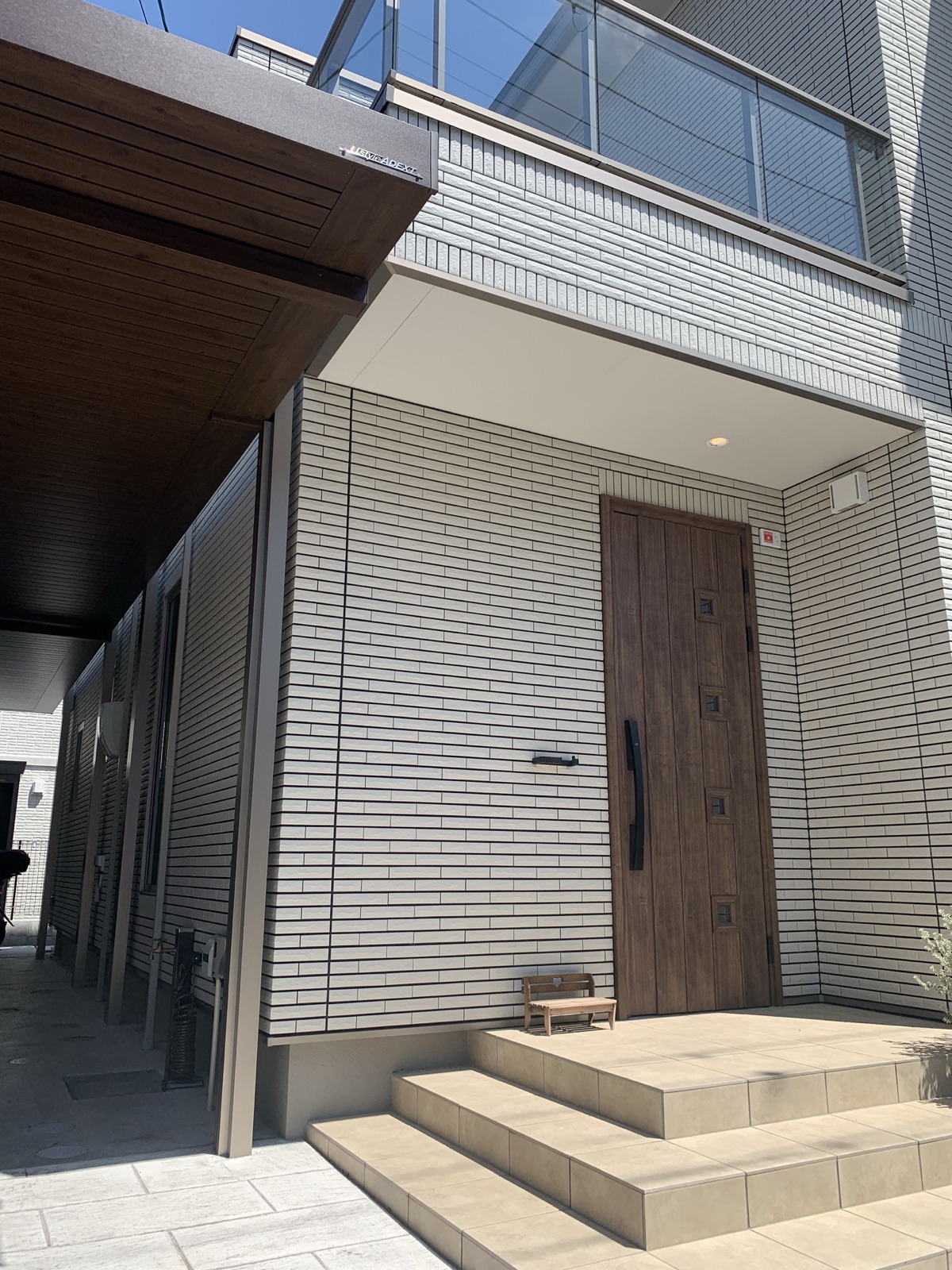 青空の下に建つ一条工務店の住宅玄関と白いタイル外壁
